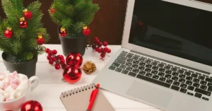 Laptop, notes i świąteczne dekoracje na biurku – praca biura w okresie świąteczno-noworocznym