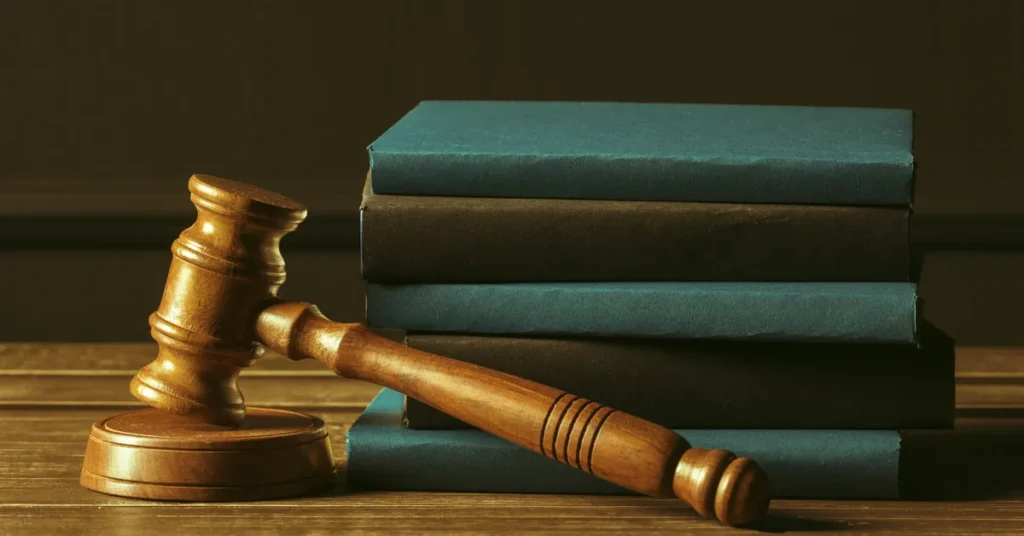 Drewniany młotek sędziowski i stos książek prawniczych – wykład o prawie pracy